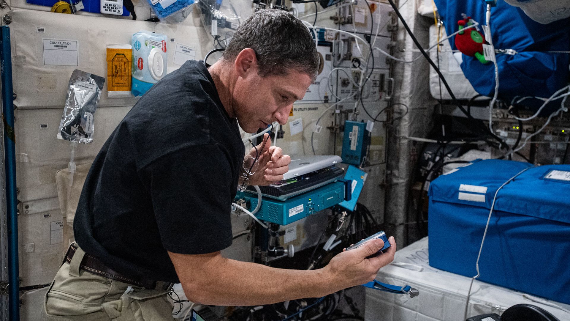 Mike Hopkins looks down at a blue container holding biological samples on the International Space Station