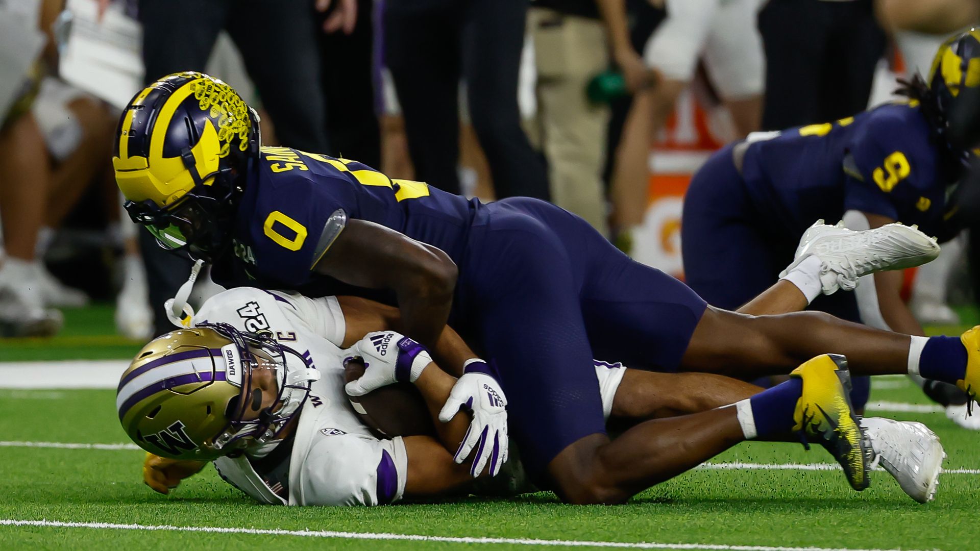 A University of Michigan football player tackles a U of Washington player during a game. 