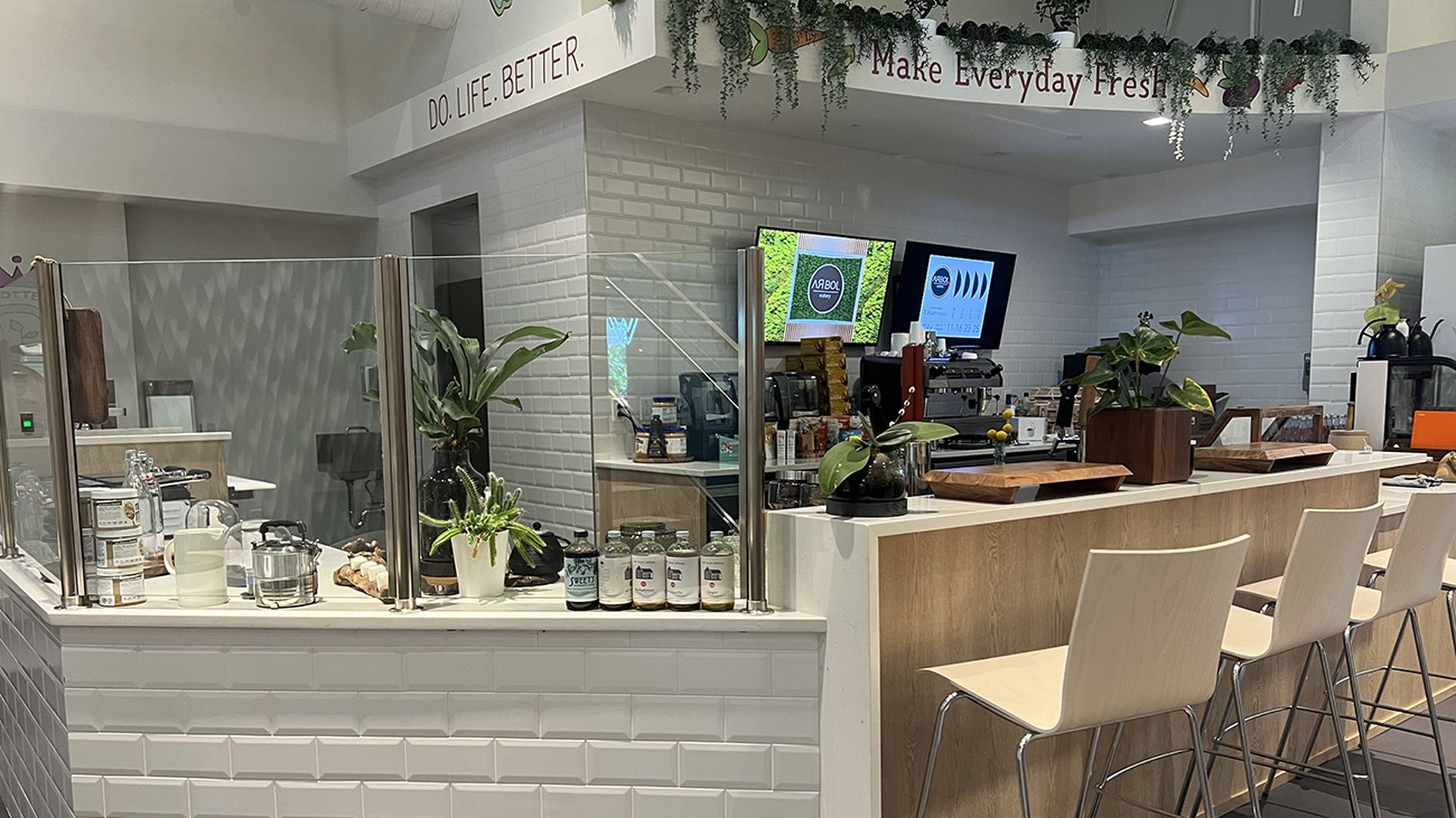 Inside of a cafe with stools lined up in front of the bar.