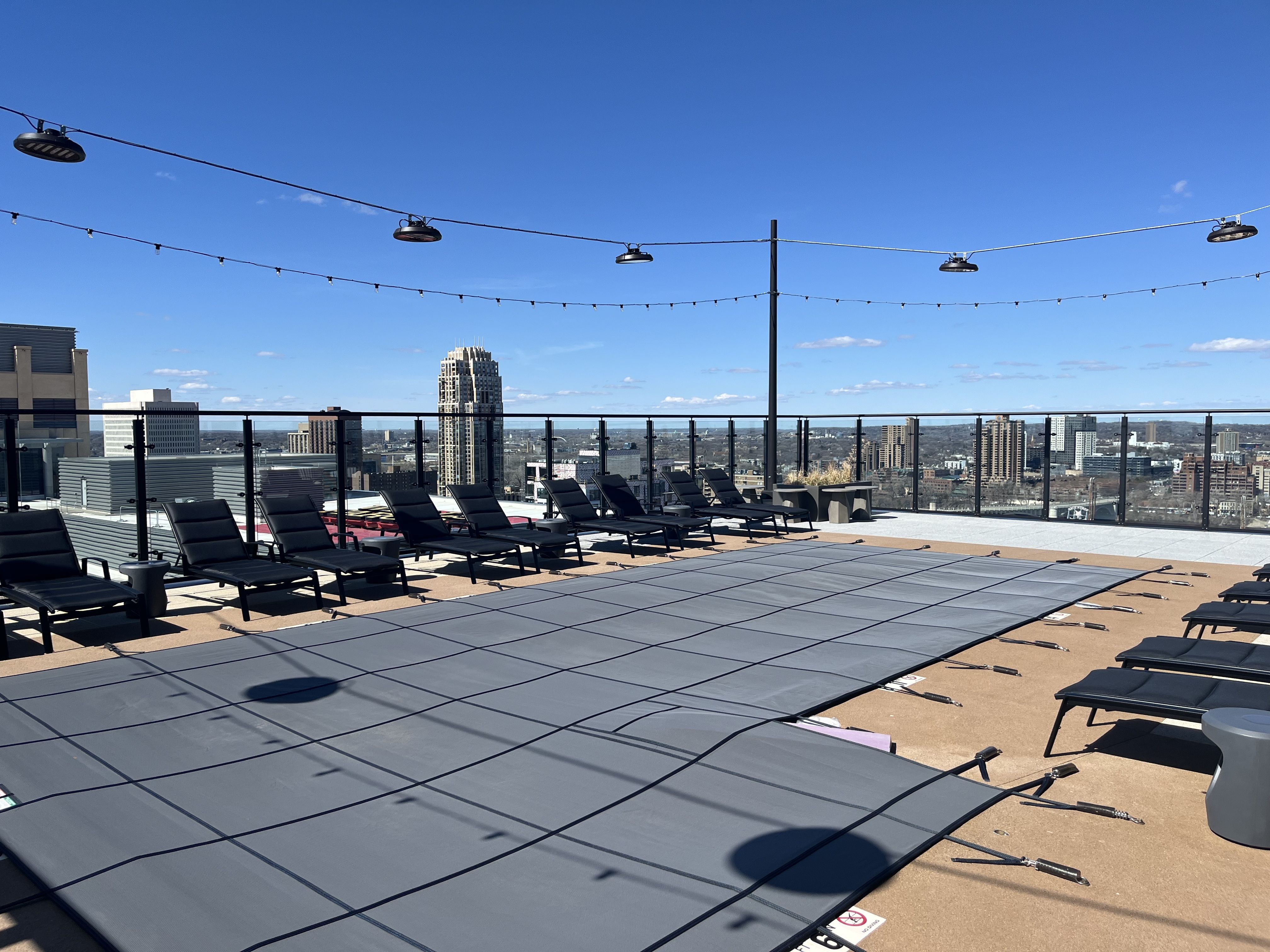 A covered pool surrounded by chairs, with the Mill District skyline in the background