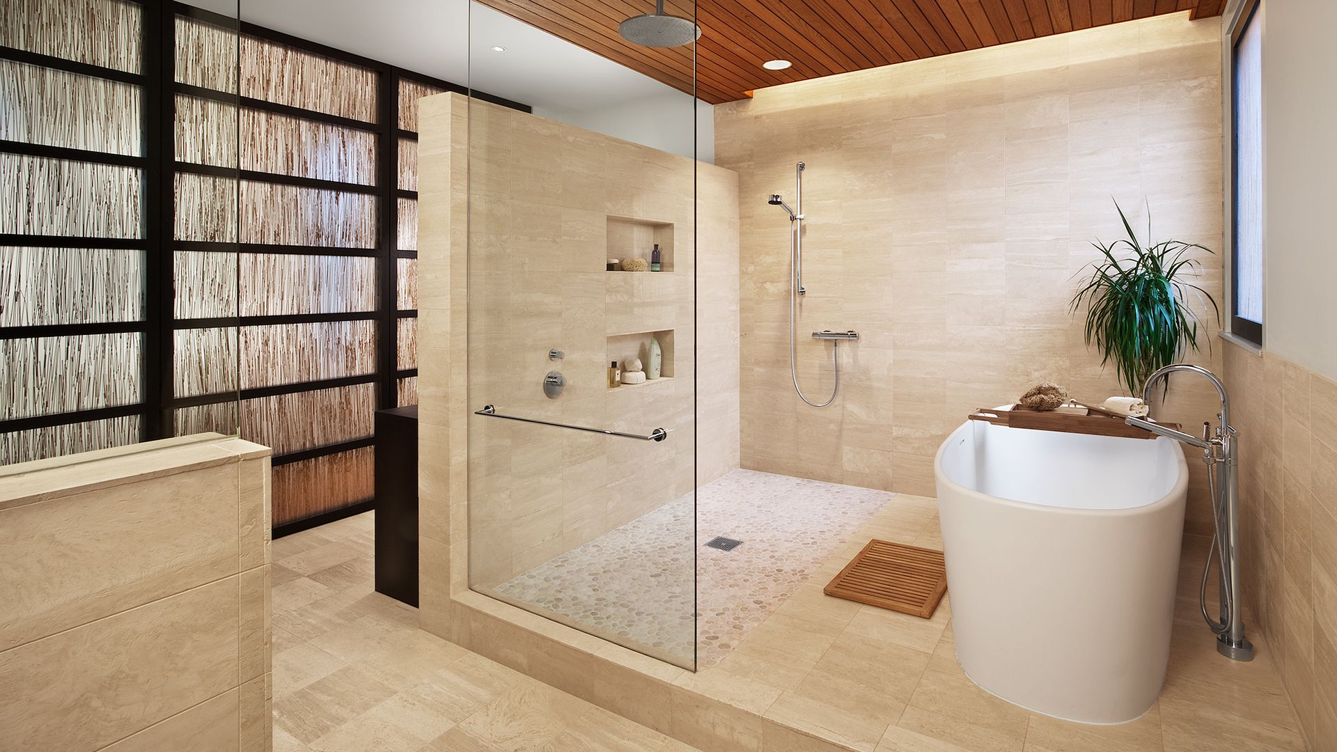 A photo showing a Chicago bathroom with a large shower and tub. Near the tub is a window and a plant. To the left of the frame is a bamboo wall that looks almost like a bookshelf.