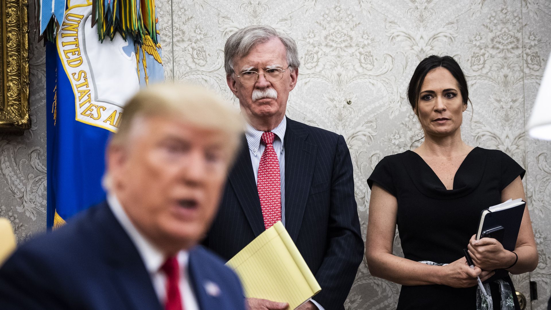 Stephanie Grisham and John Bolton look on as Trump speaks