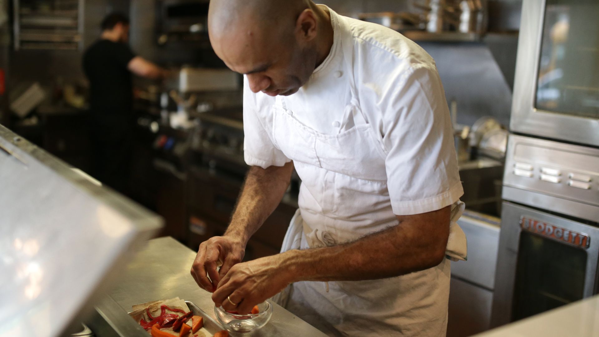 MIDA chef/owner Douglass Williams looking down, working on a plate in the restaurant kitchen in the South End