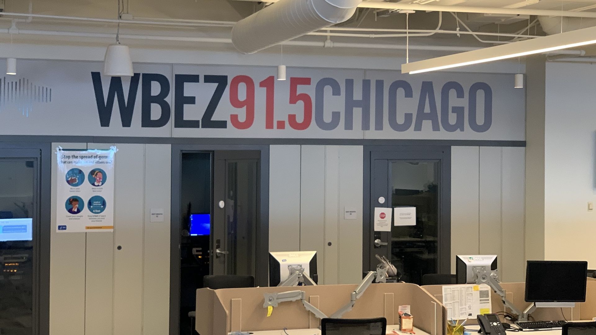Inside of newsroom with computers and WBEZ91.5Chicago sign.