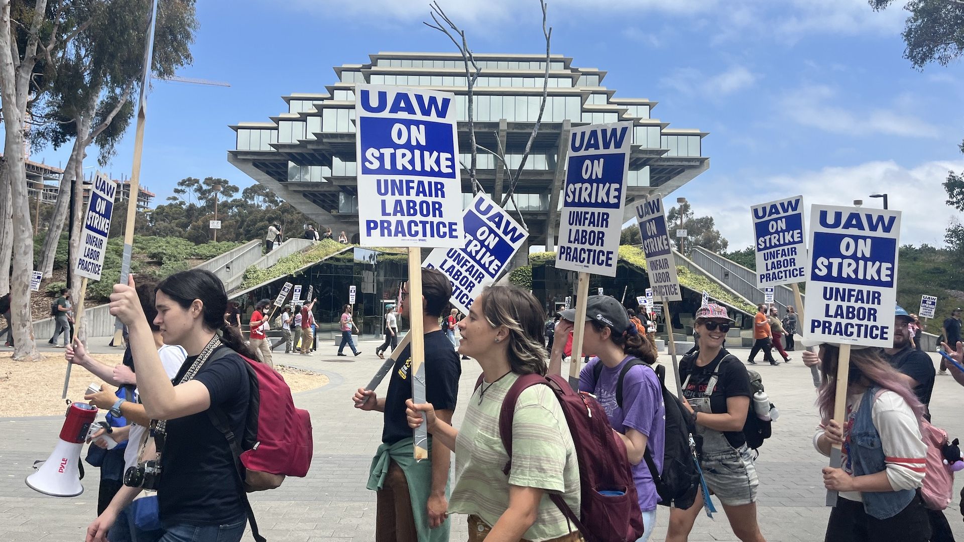 Academic workers hold signs and chant while strike at UC San Diego's campus.