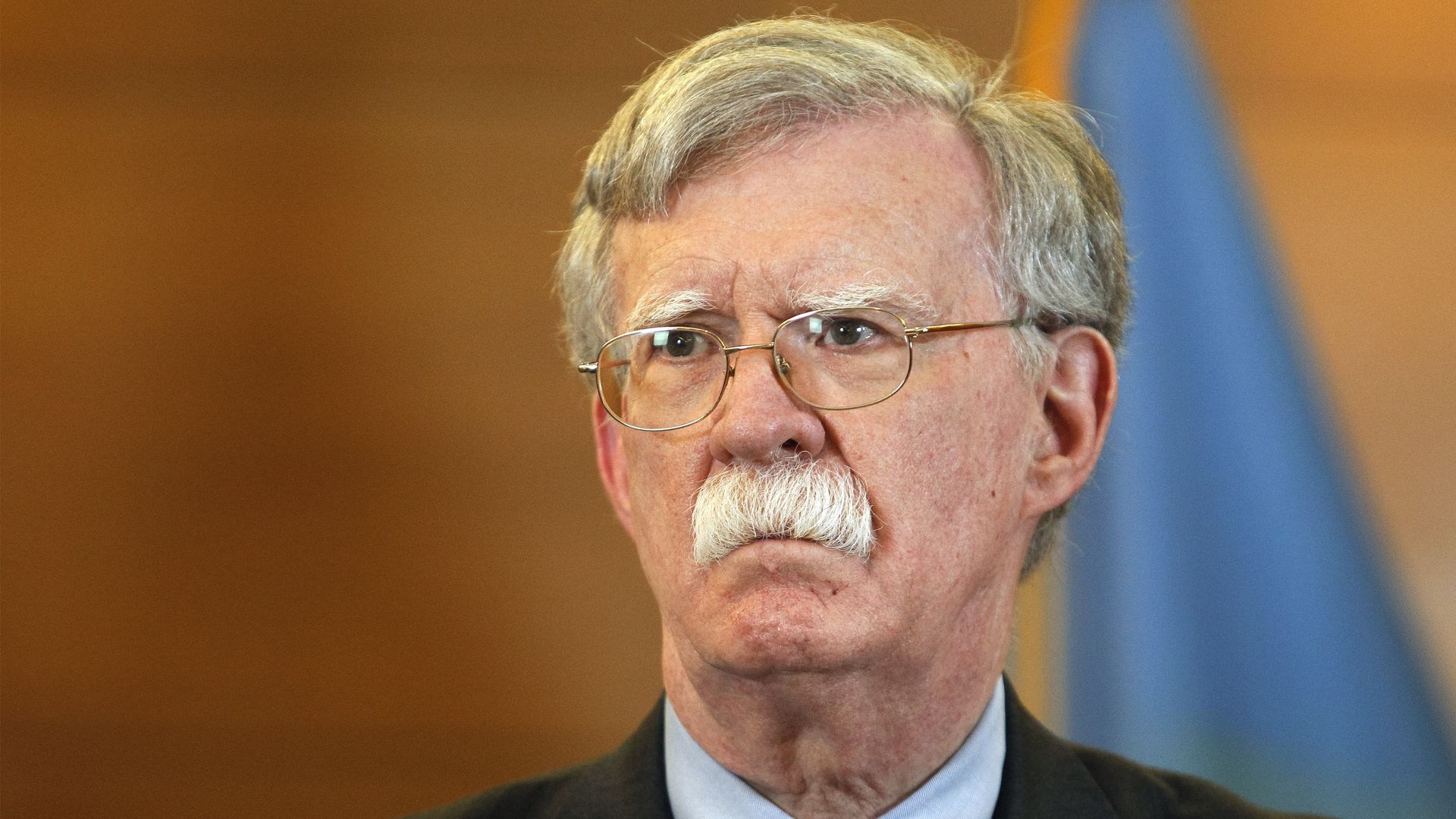 John Bolton in front of a Ukrainian flag