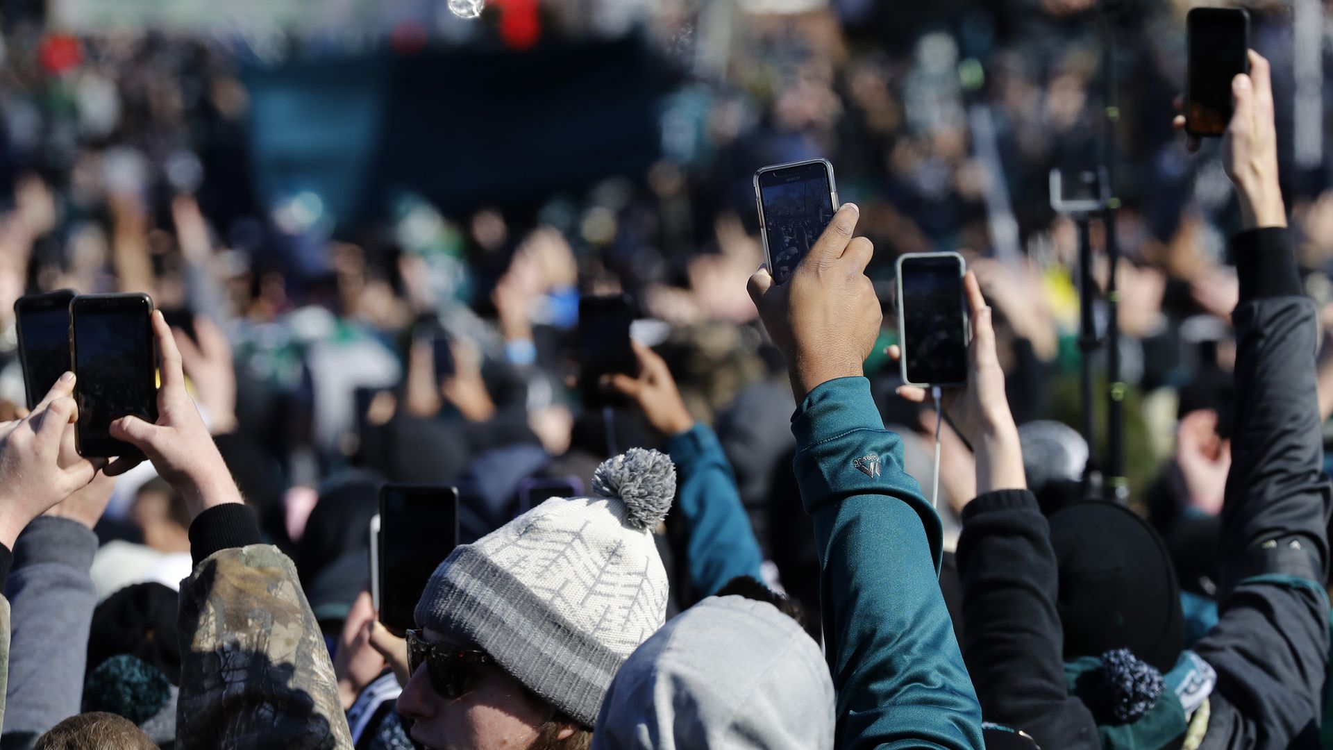 People hold their cell phones up in a crowd.