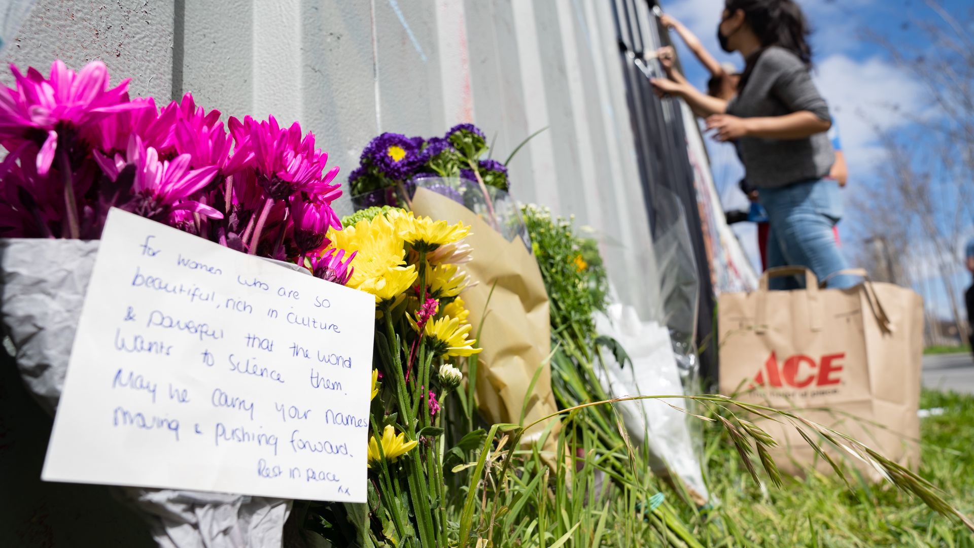 Photo of flowers and a note sitting at the foot of a wall 