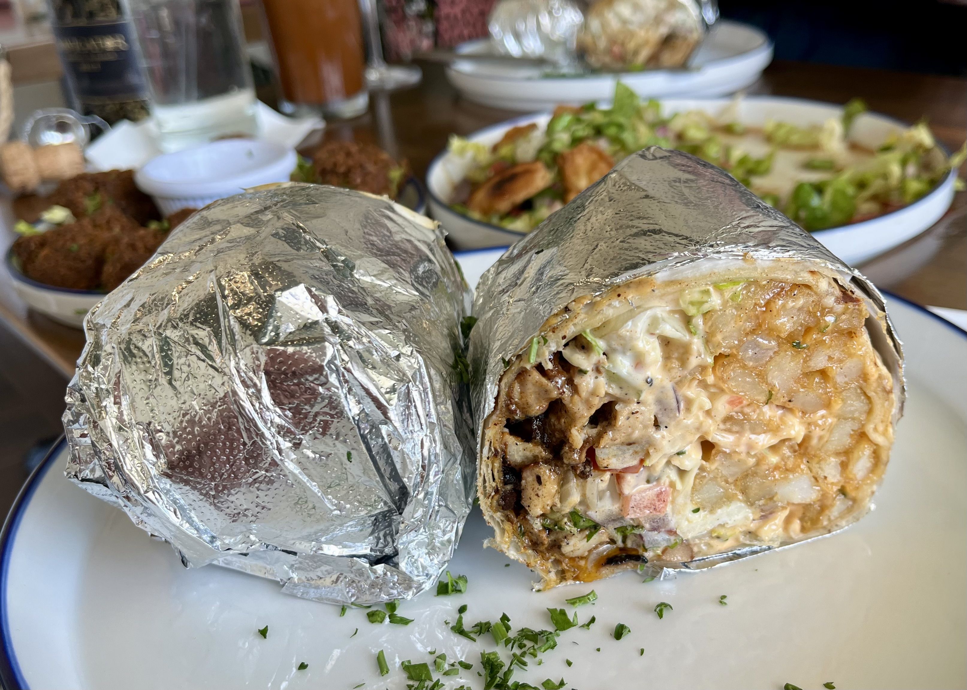 A burrito cut in half to show the chicken, French fries and sauce fillings.