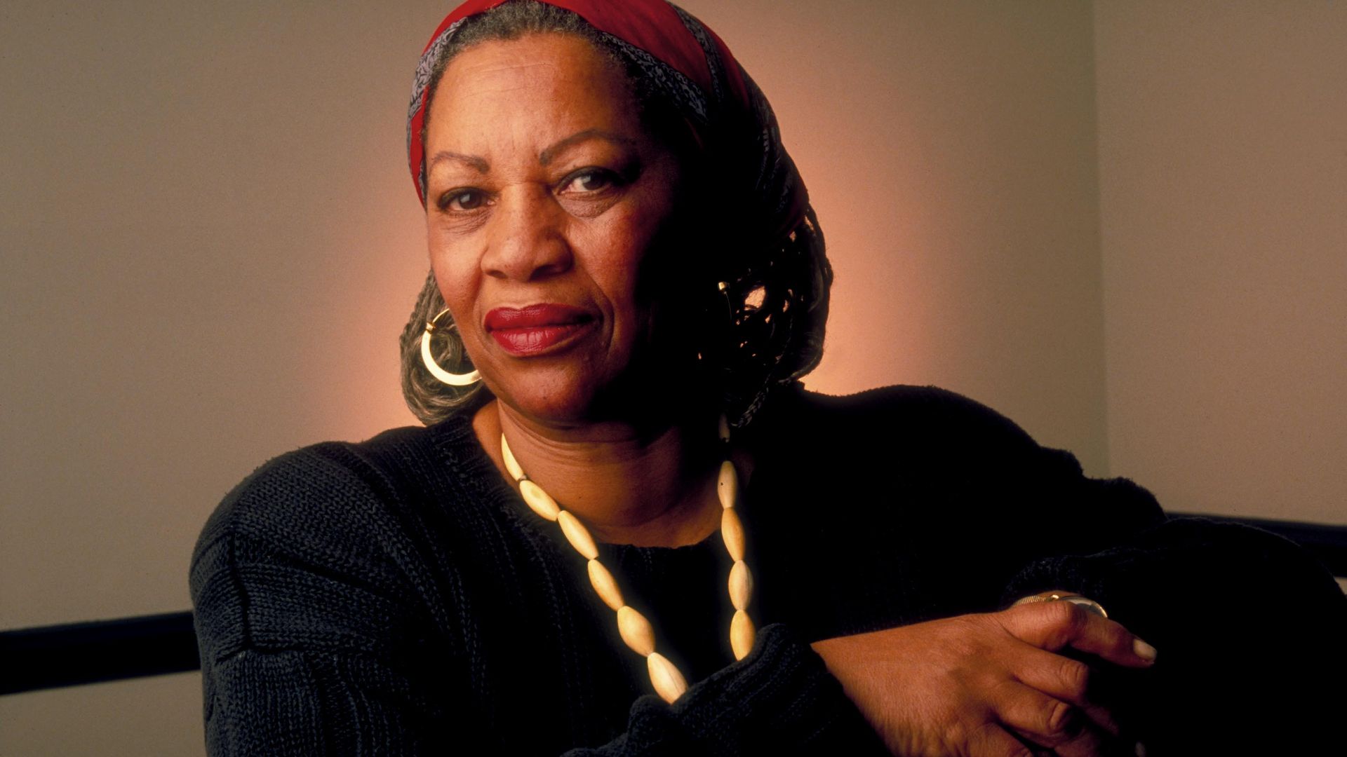 Photo of a black woman in a black sweater and seashell necklace with hoop earrings 