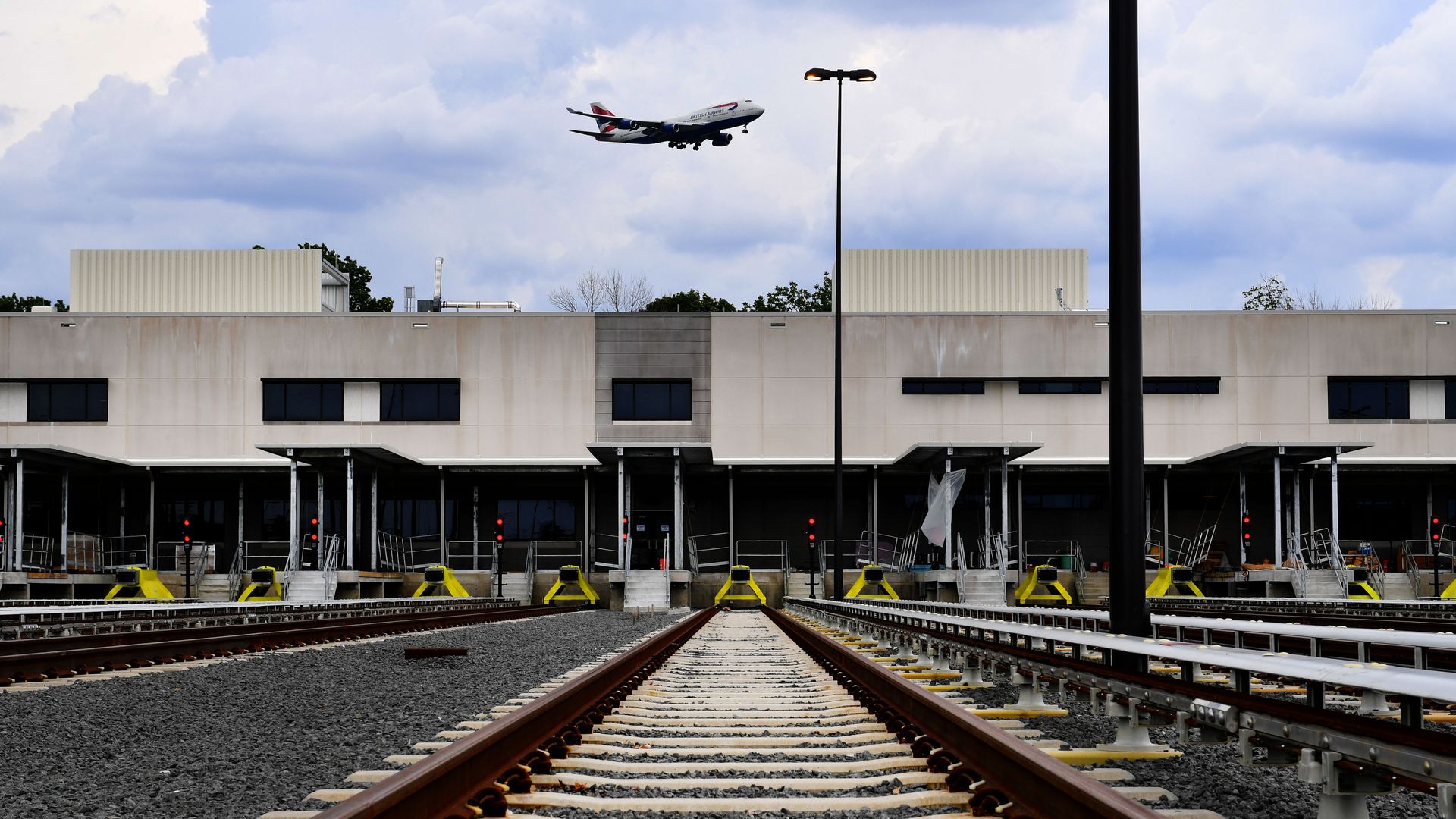 A plane flies over the WMATA rail yard at Dulles Airport.