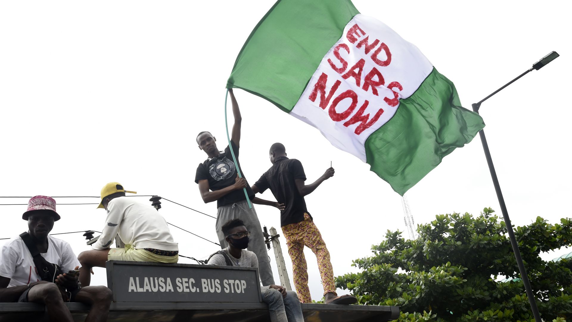 Photo of a person waving a Nigerian flag that says "End SARS now" 