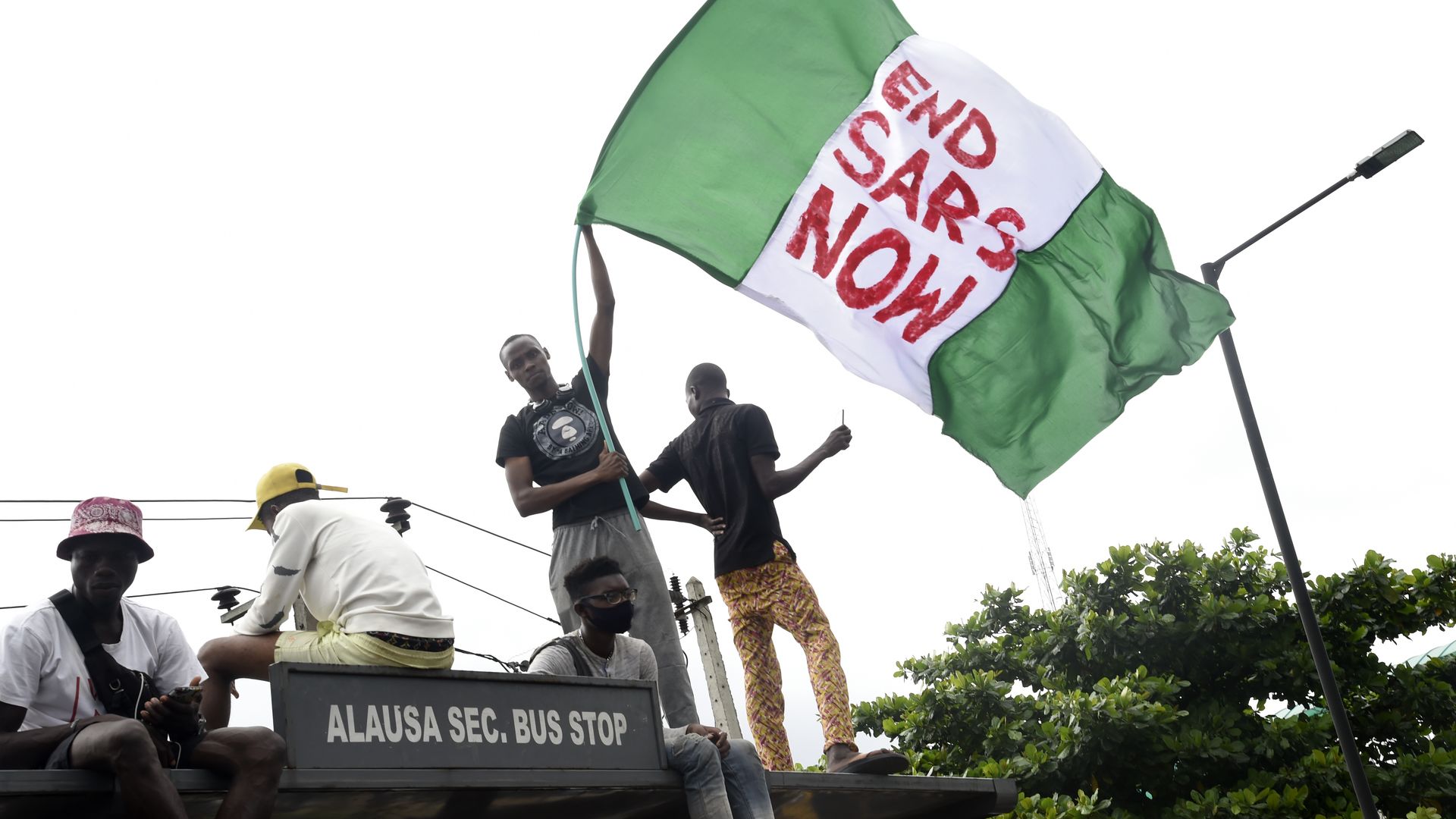 Photo of a person waving a Nigerian flag that says "End SARS now"