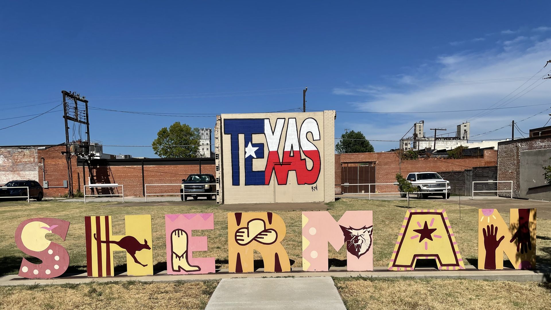 A sign that spells out Sherman in front of a wall painted to say TEXAS