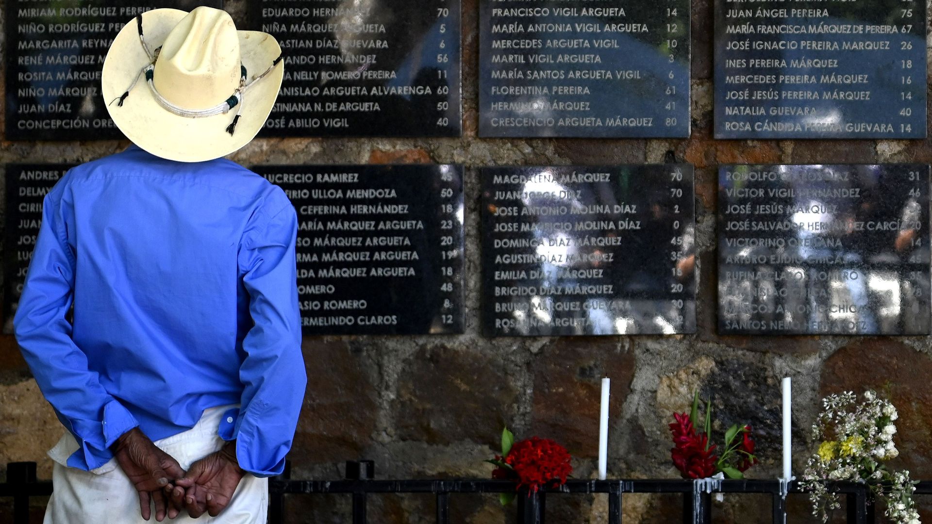 A man reads the names of the victims of the El Mozote, El Salvador, on a memorial commemorating the massacre. 