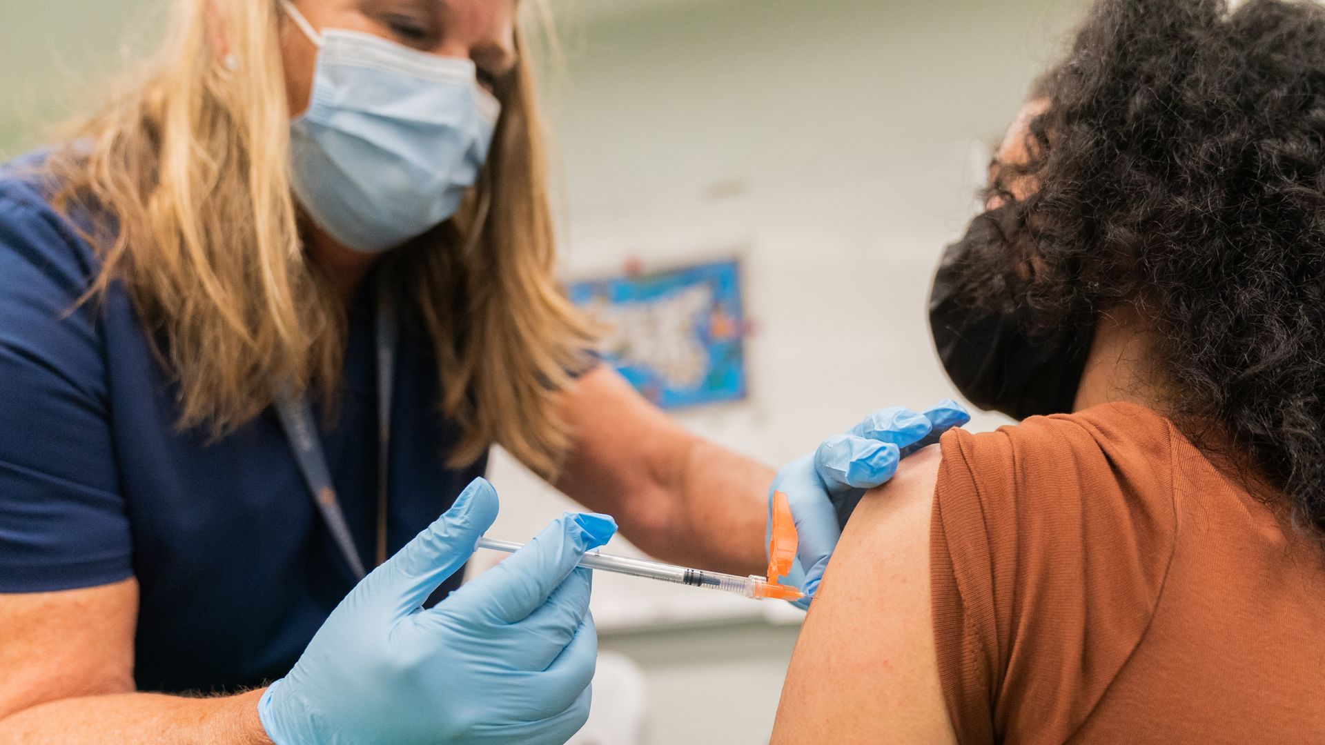 A health care worker administering a dose of coronavirus vaccine to a student in Staten Island in August 2021.