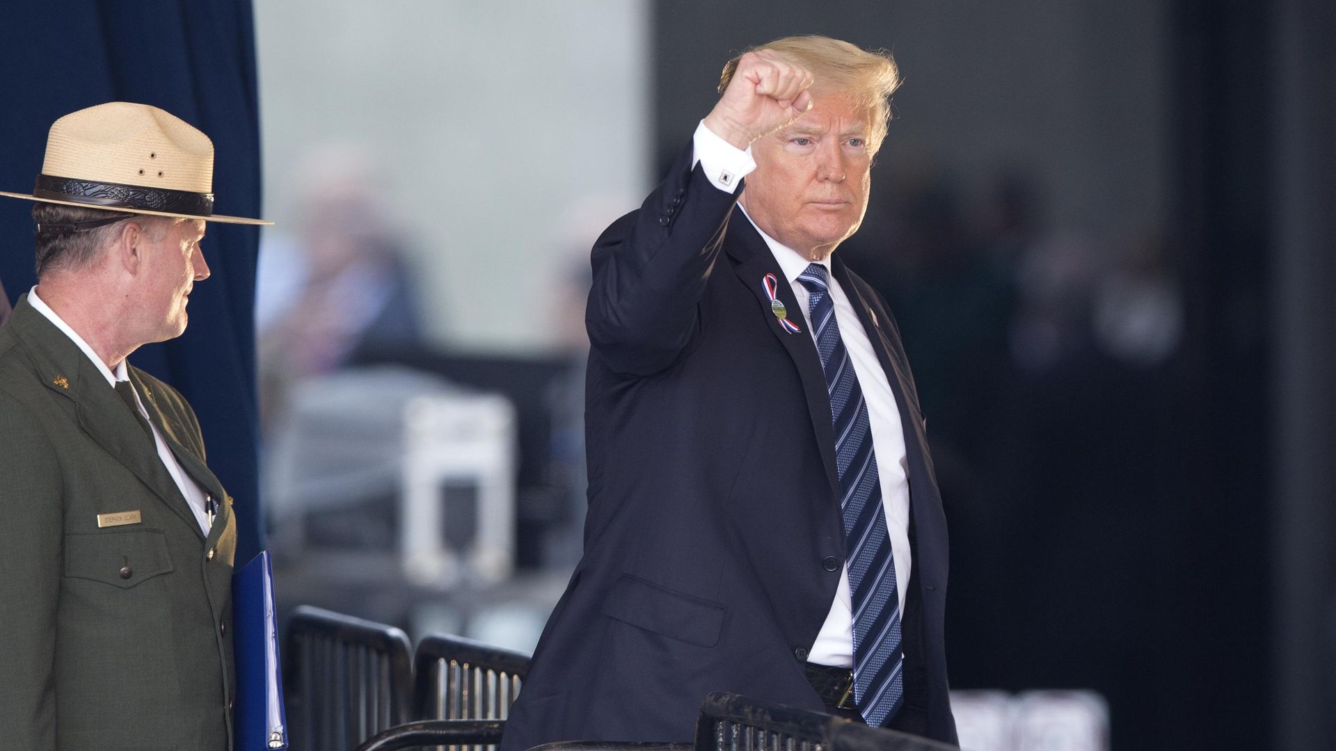 Donald Trump walking off a stage with his right hand up in a fist