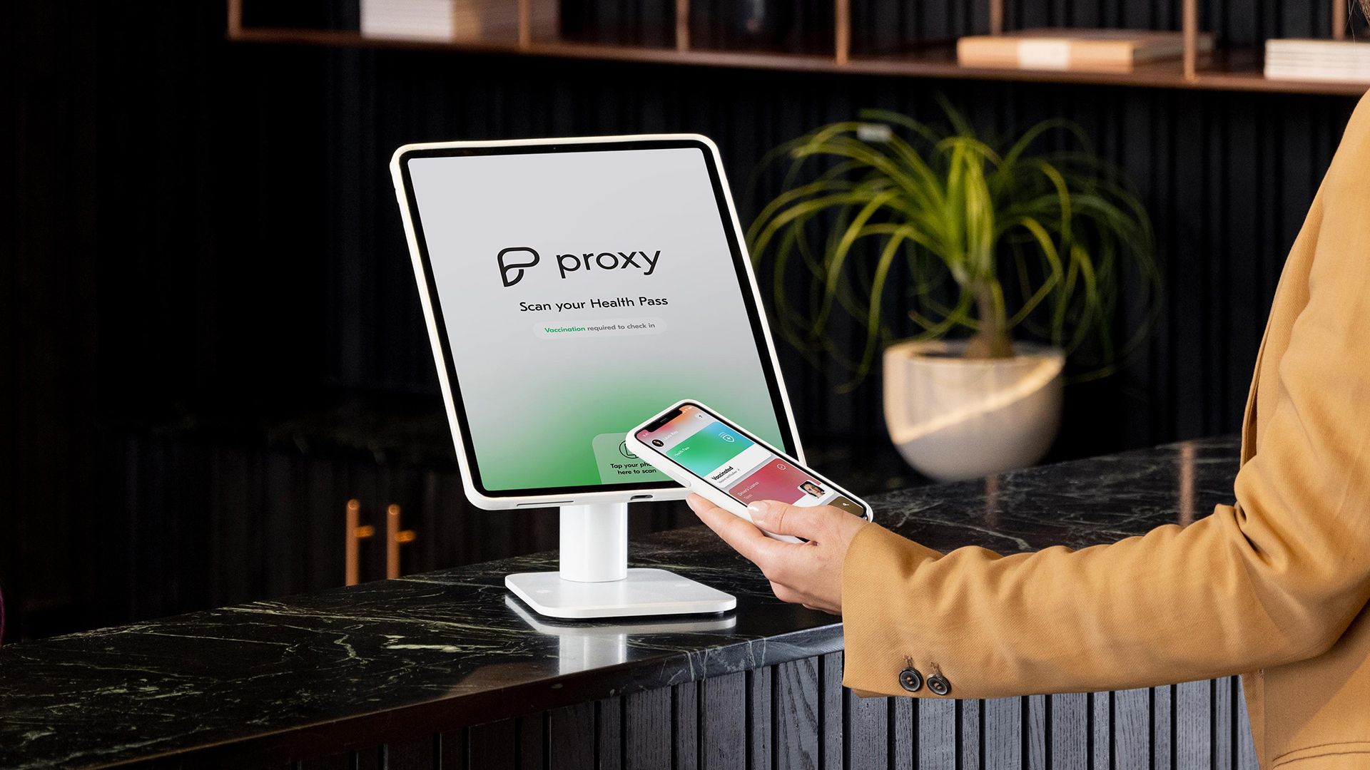 A person stands with a smartphone pulling up the Proxy Health app