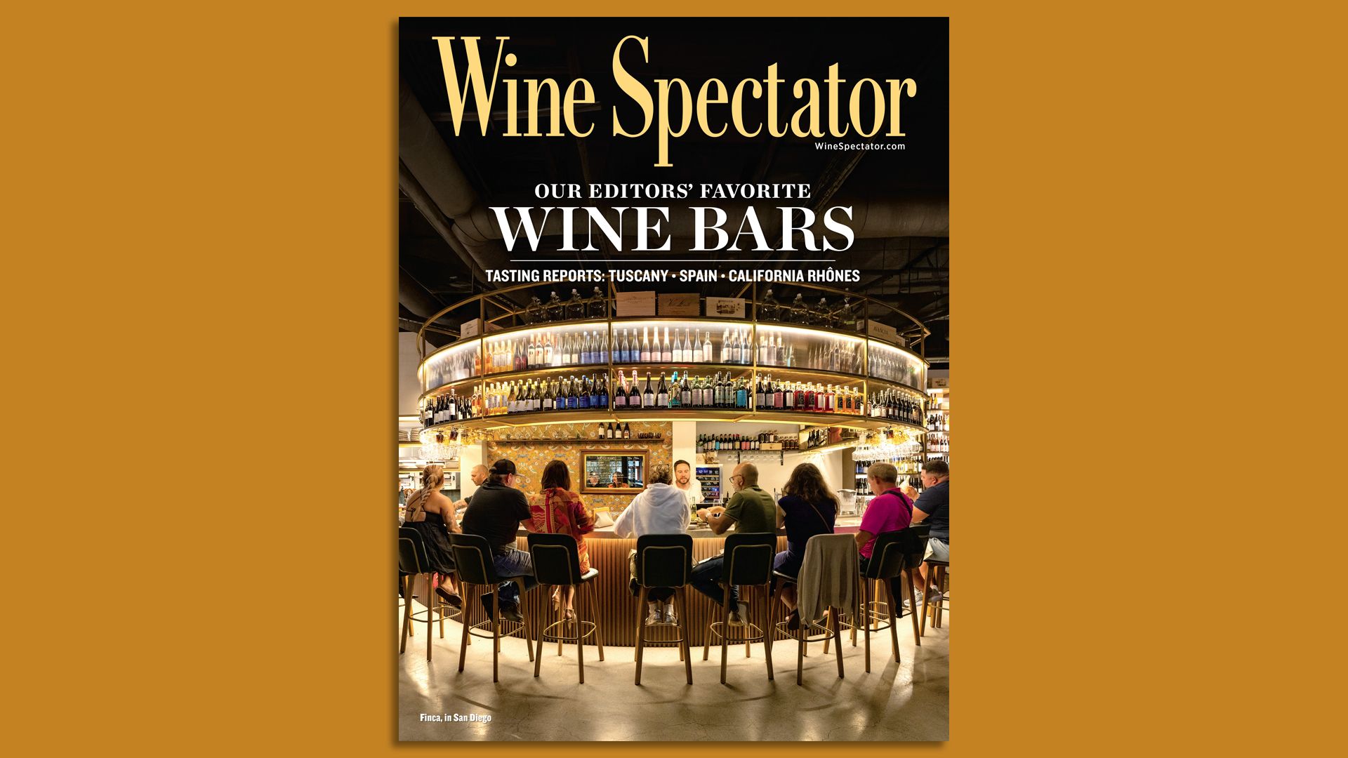Cover of Wine Spectator magazine showing the interior of Finca wine bar, with a modern circular bar with people seated on stools, shelves of wine bottles, and warm lighting.