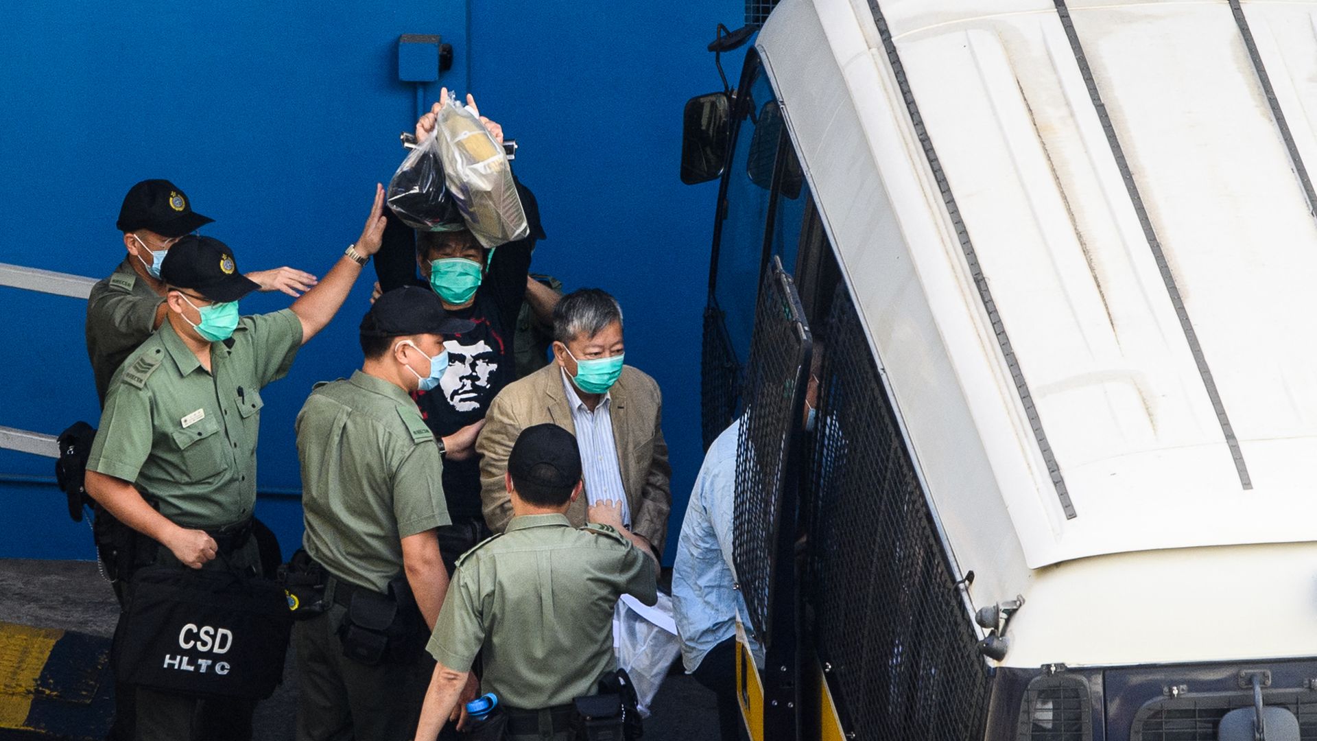 Pro-democracy activists Leung Kwok-hung (center left) beside a prison van in Hong Kong.