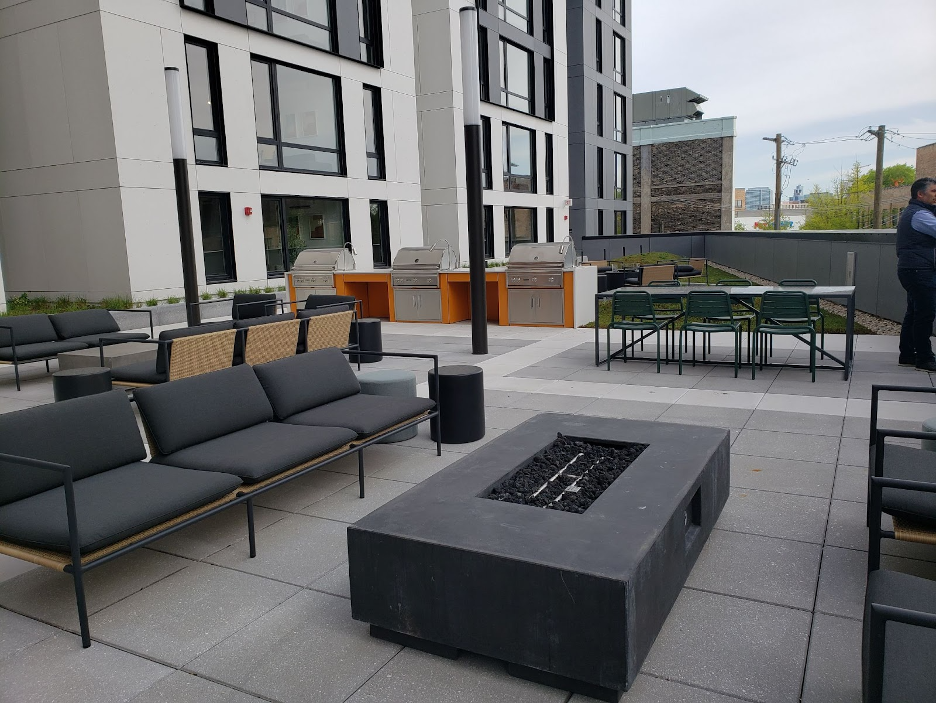 Fire pits, grey couches and grills on an outdoor patio communal area at Post Chicago.