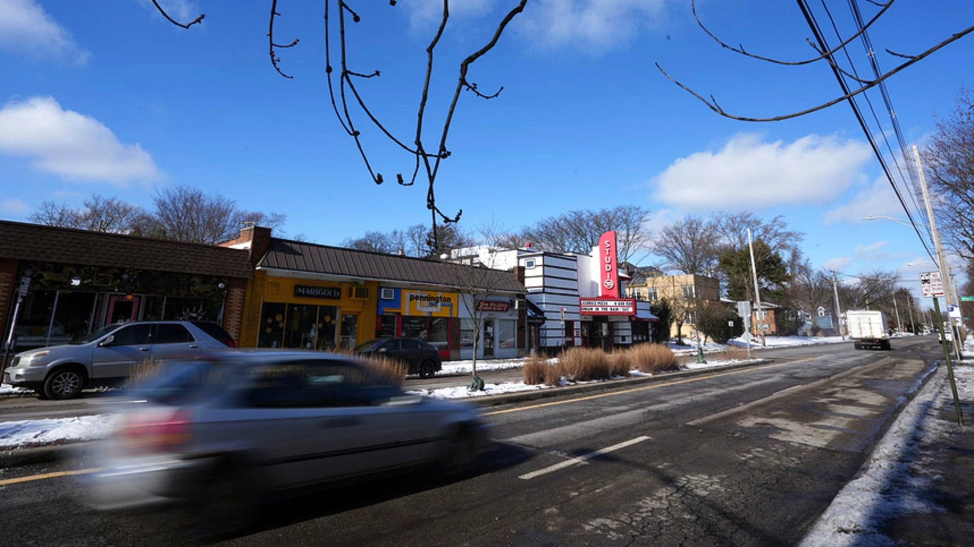 A car speeds by local businesses on Columbus' Indianola Avenue.