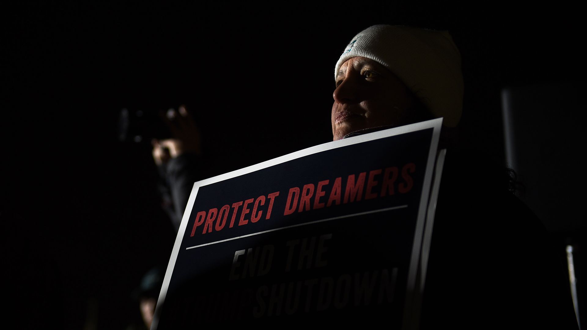 Woman carrying a "protect dreamers" sign. Dark photo