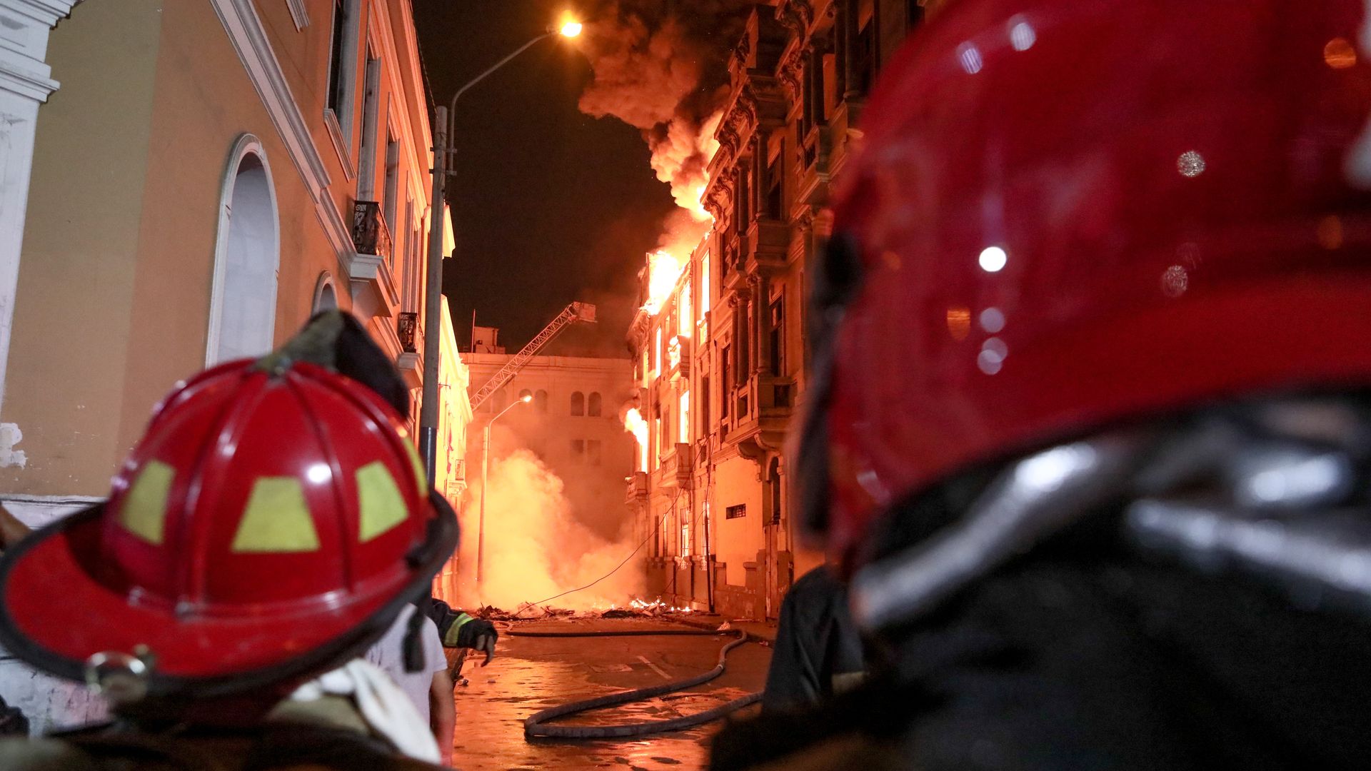 Firefighters extinguishing fire at a building where a fire broke out at the roof during the clashes between protestors and demonstrator in f Lima, Peru on January 19, 2023. 