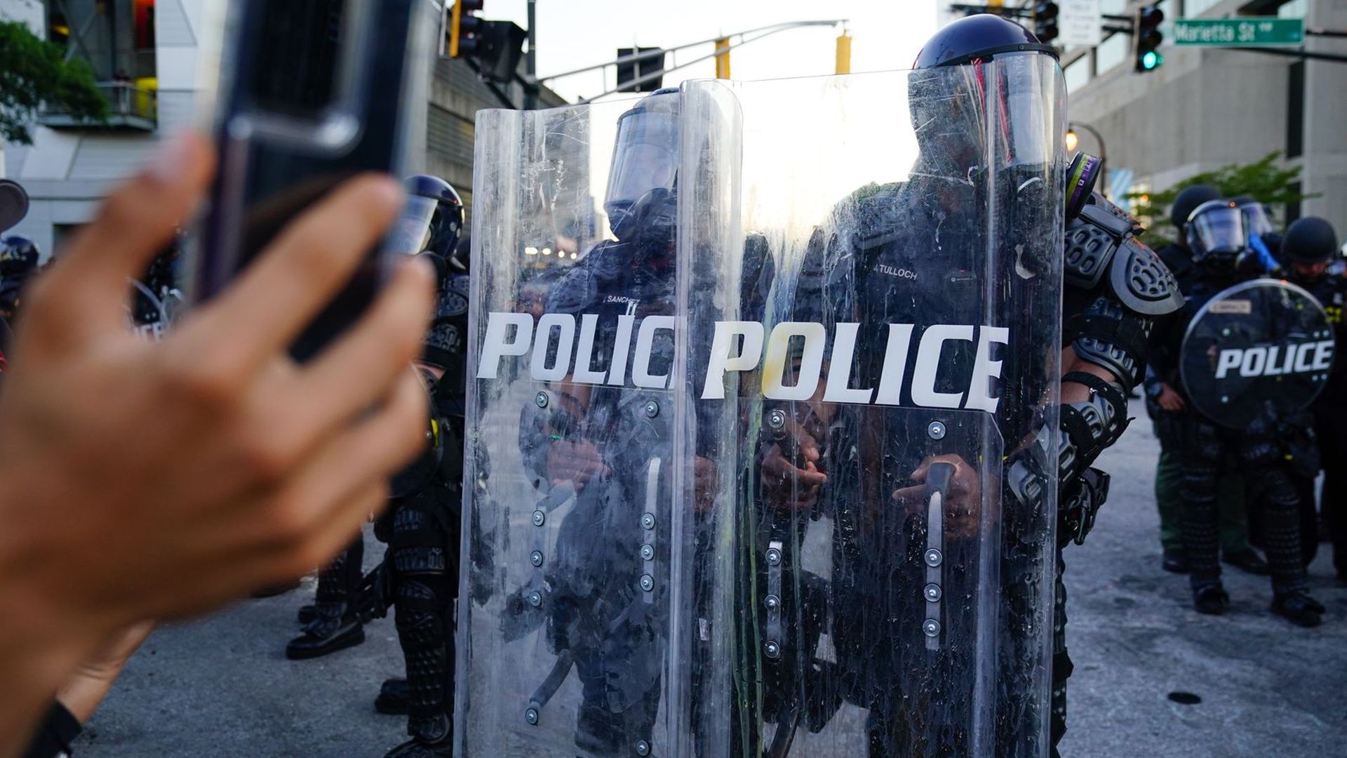 A man records video of a police line during a 2020 Atlanta protest in response to the police killing of George Floyd in Minnesota. Photo: Elijah Nouvelage/Getty Images