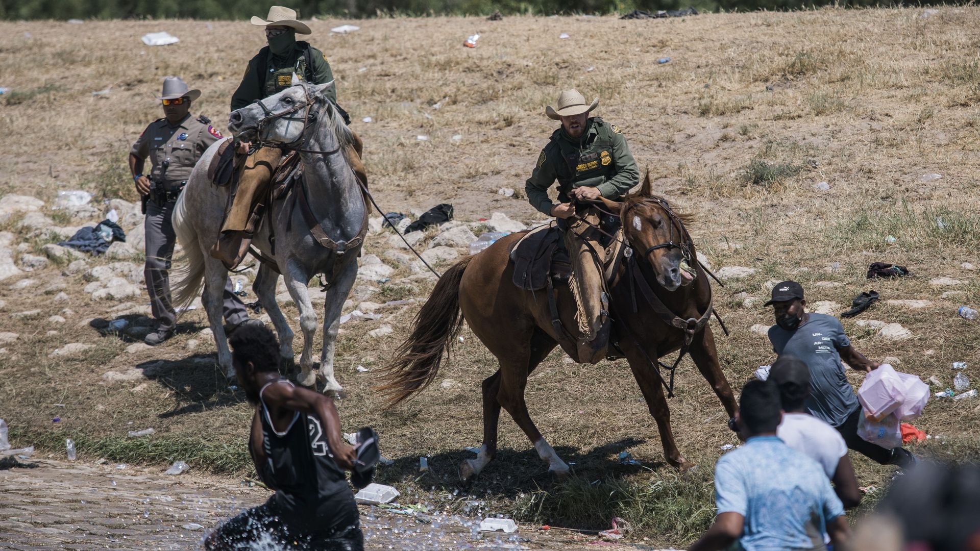 U.S. Customs and Border Protection mounted officers attempt to contain migrants as they cross the Rio Grande on Sunday.