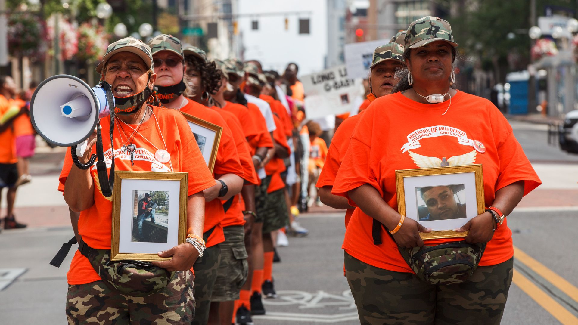 Malissa Thomas-St. Clair leads a Mothers of Murdered Columbus Children march downtown on the streets in 2021. The group is in orange shirts and carrying framed photos of their children.