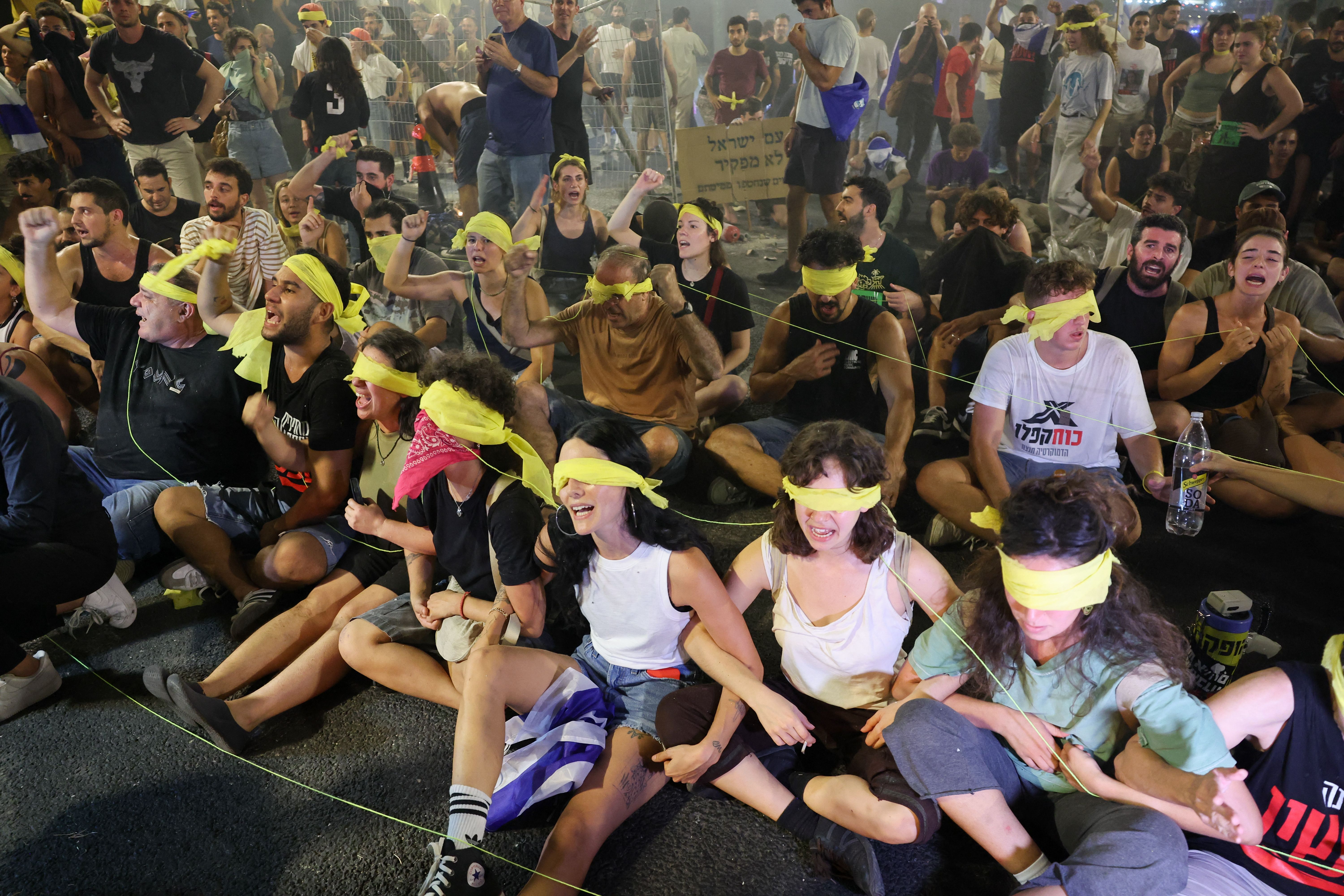Protesters, wearing a yellow blindfold, sit on the ground during an anti-government rally calling for the release of Israelis held hostage by Palestinian militants in Gaza since October, in Tel Aviv on September 1, 2024.
