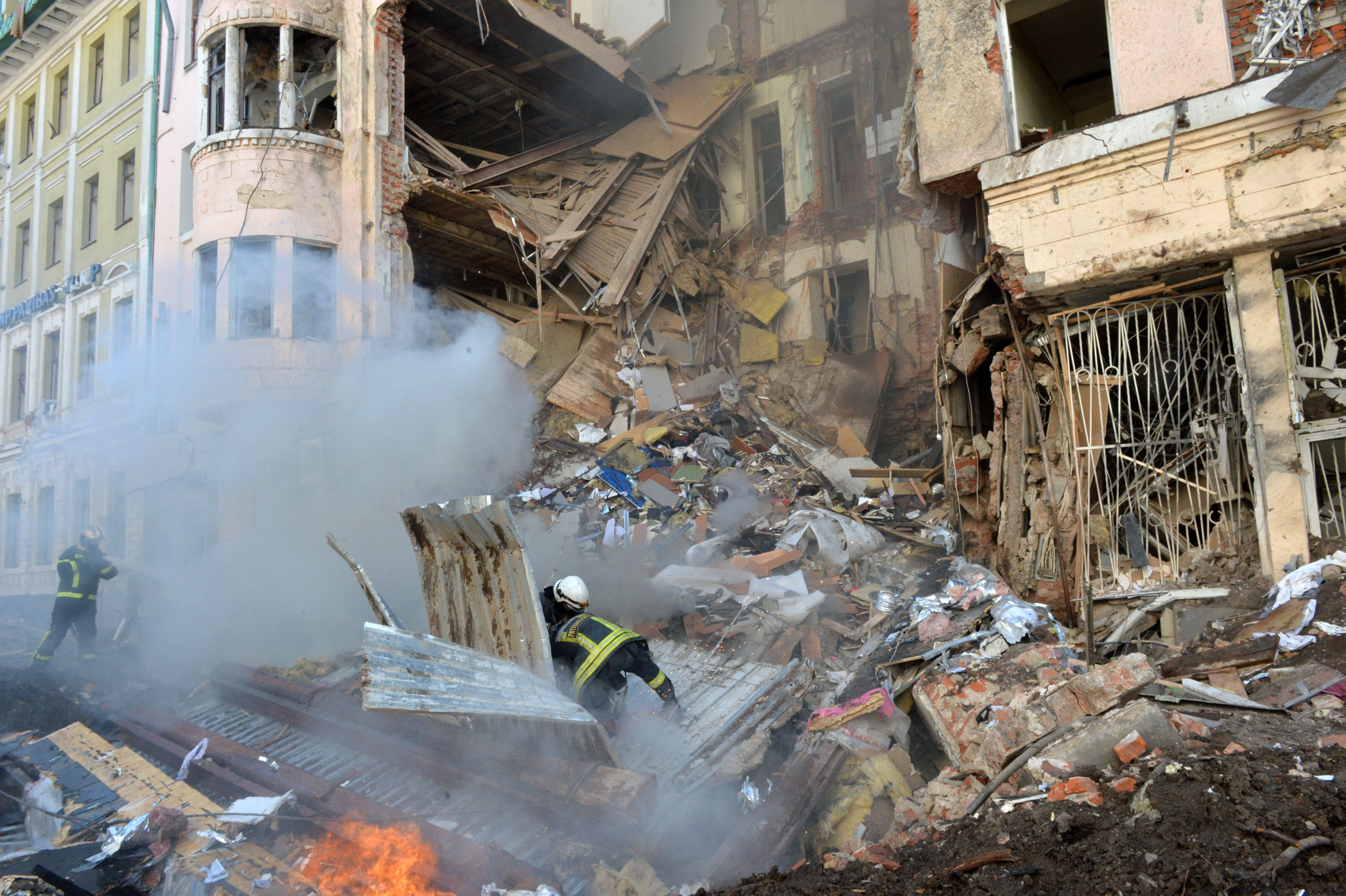 Firemen work to clear the rubble and extinguish a fire by a heavily damaged building after a Russian rocket exploded just outside it in Ukraine's second city Kharkiv on March 14.