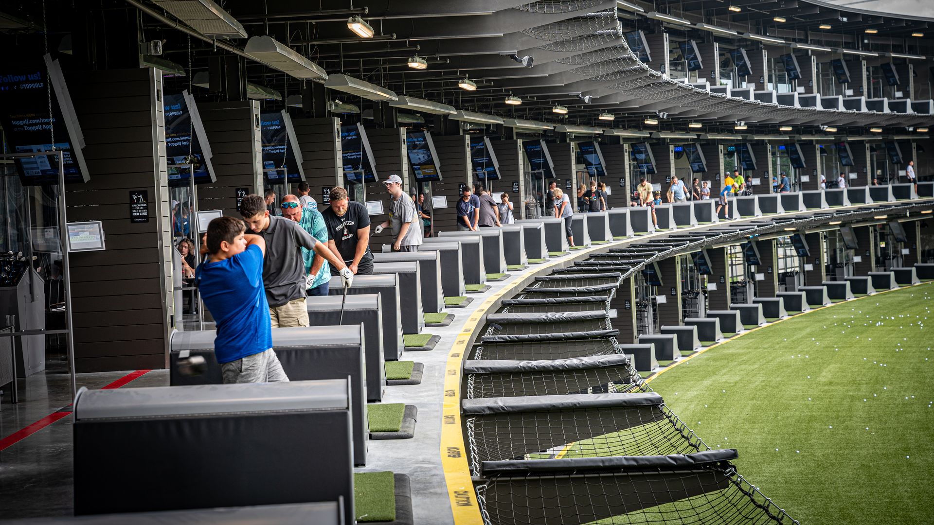 A photo showing people hitting golf balls at a Topgolf