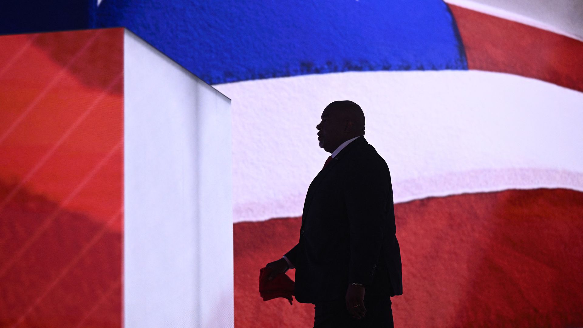 Mark Robinson walks in front of an American flag at the RNC