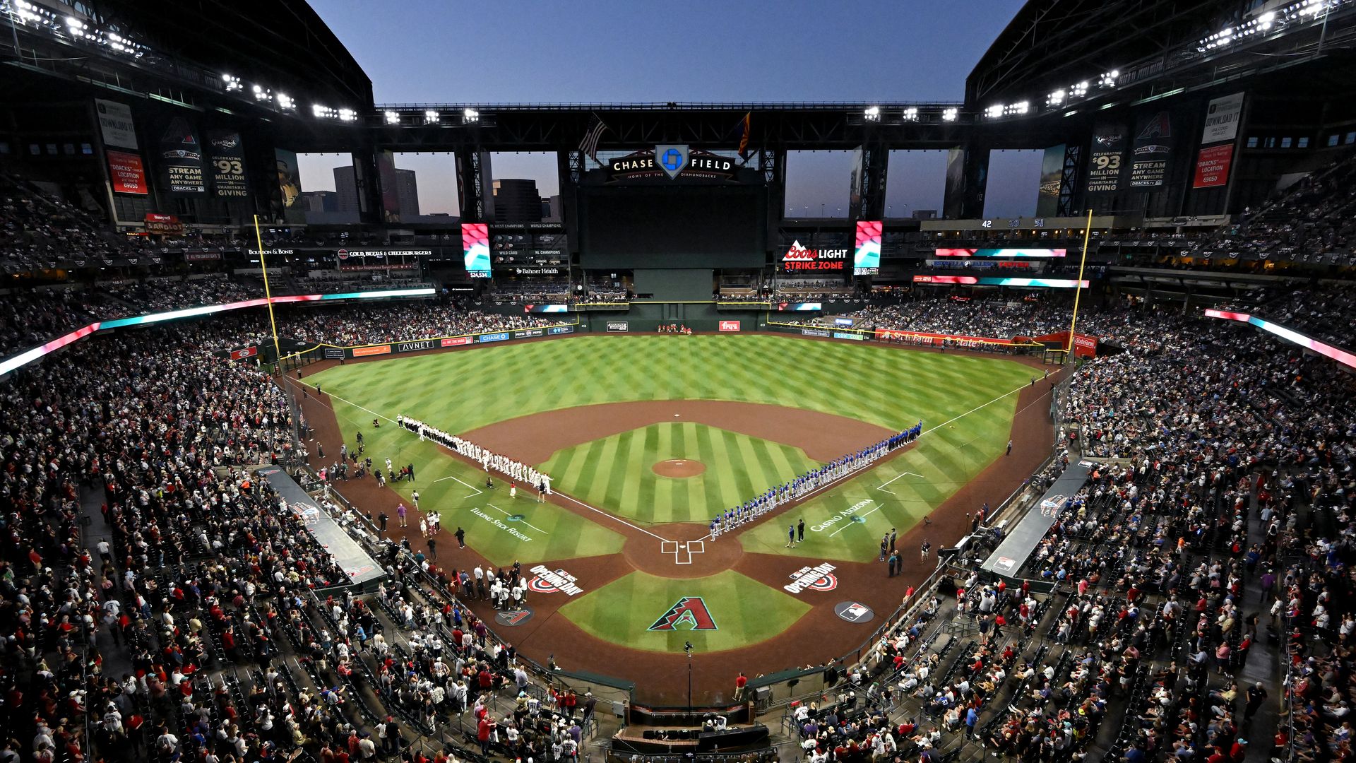 A view from high up behind home plate of Chase Field's baseball field, with fans in the stands and the roof open.