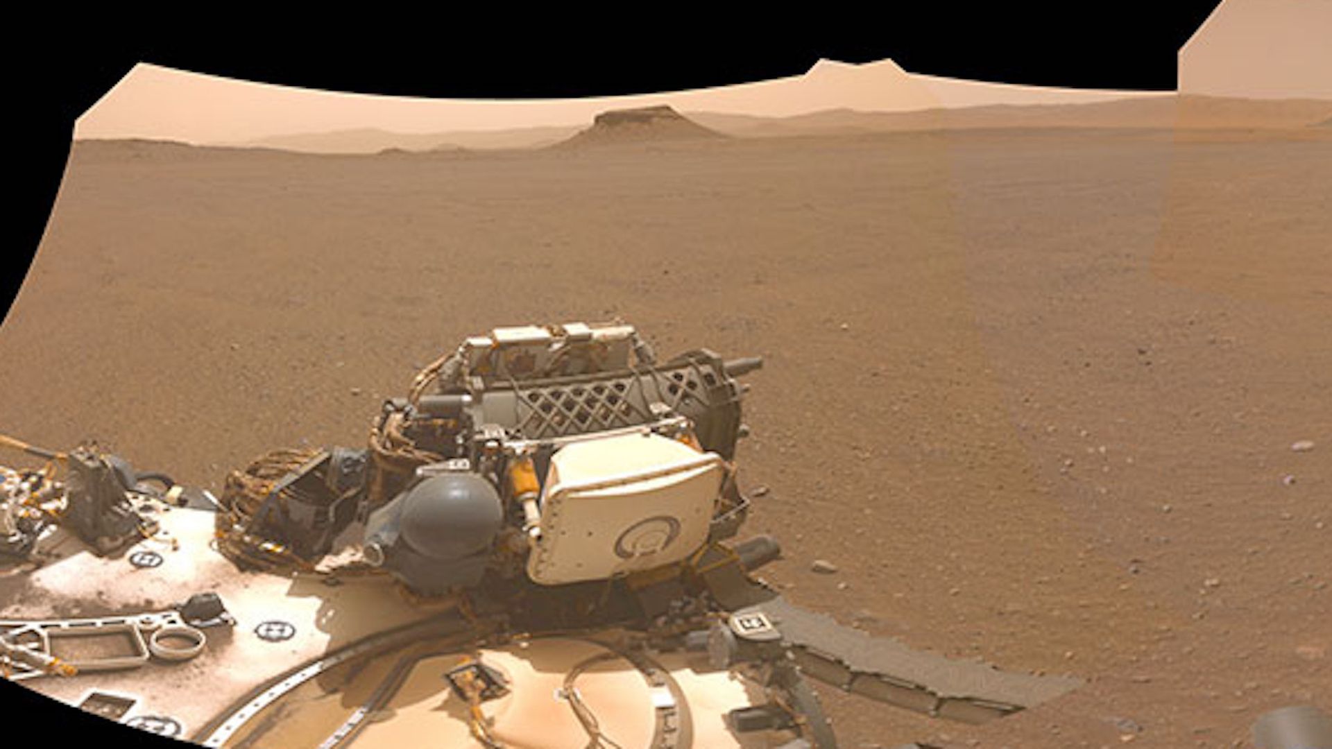 Perseverance looking out on Mars. The spacecraft is foregrounded, with a large plane stretching out in front of it.