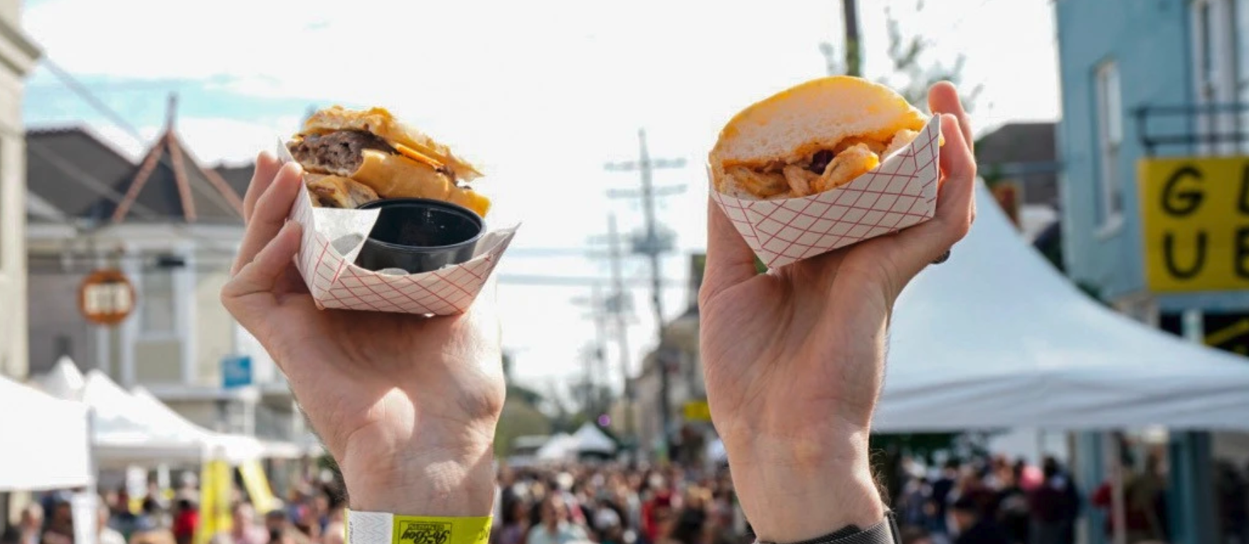Photo shows people holding poboys in the air.