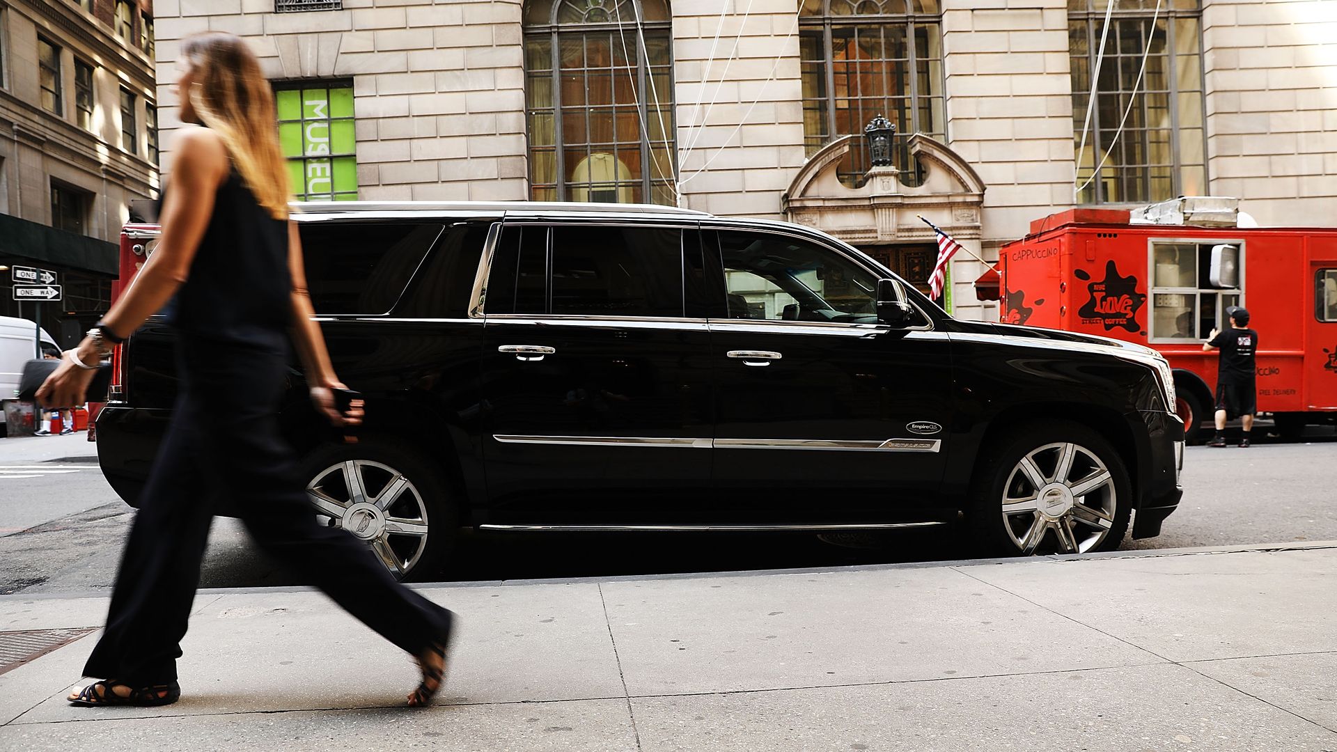 A woman walks by an SUV on the street. 