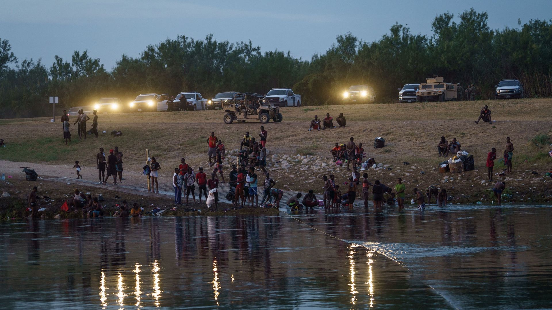 US Border Patrol, National Guard and Texas Department of Public Safety vehicles in Del Rio, Texas, shine their lights on the crossing point for mostly Haitian migrants on the Rio Grande,