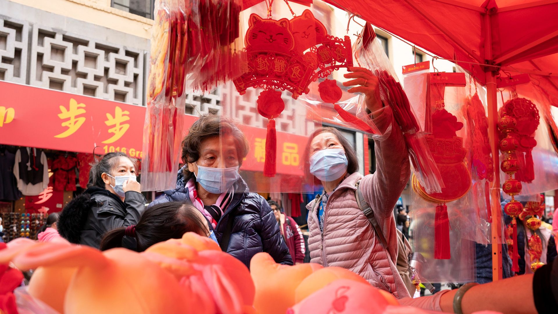 Photo of two people shopping in Chinatown streets decorated with red Lunar New Year lanterns and fans