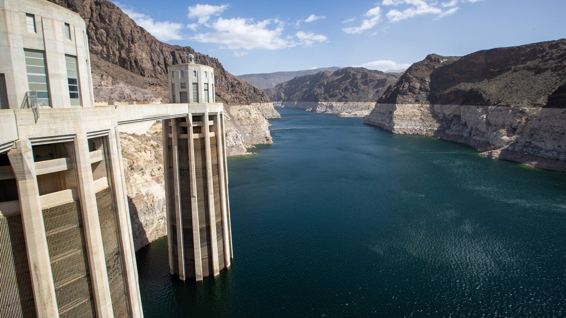Concrete pillars rise out of a lake with a white ring around it showing how far water levels have fallen.