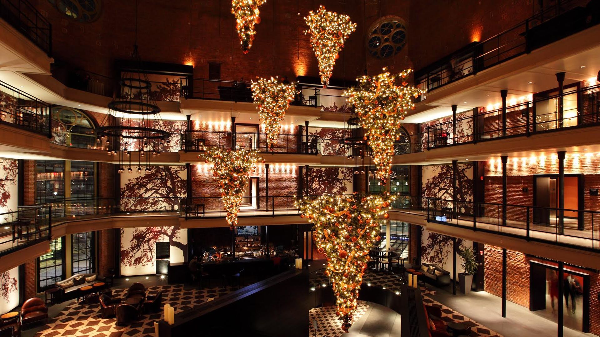 A three-story hotel lobby at the Liberty Hotel in Boston with upside down Christmas trees hanging from the ceiling.