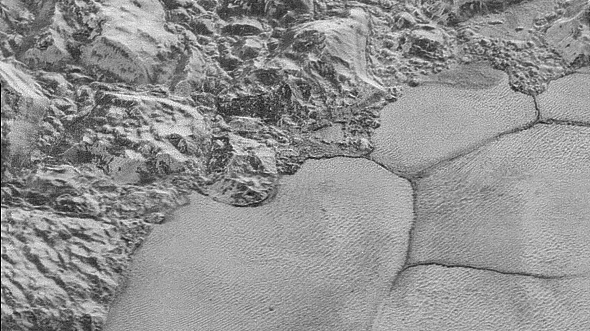 The mountain range on the edge of the Sputnik Planitia ice plain, with dune formations in the bottom half of the picture.