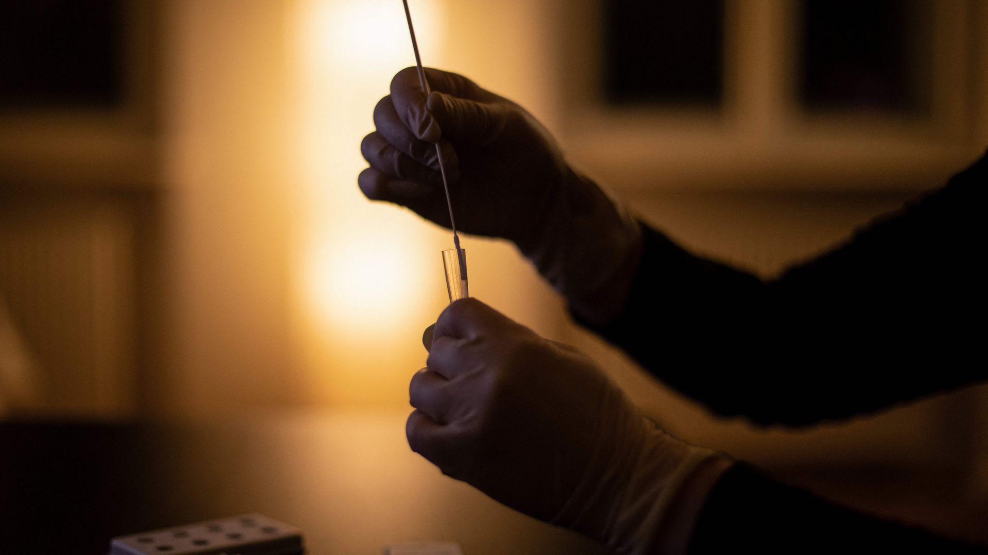 A person places a test swab into a tube for a Covid-19 test.