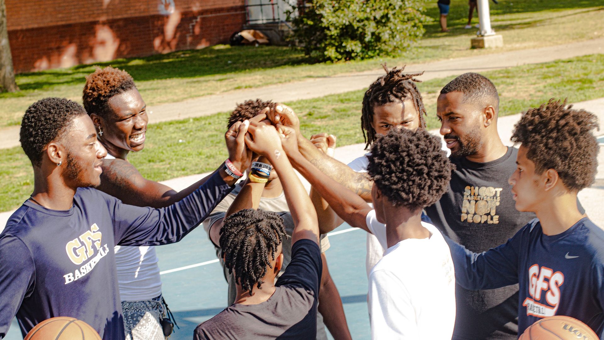 Basketball coach Garry Mills, right middle, huddles with a group of players involved in his nonprofit, "Shoot Basketballs Not People."