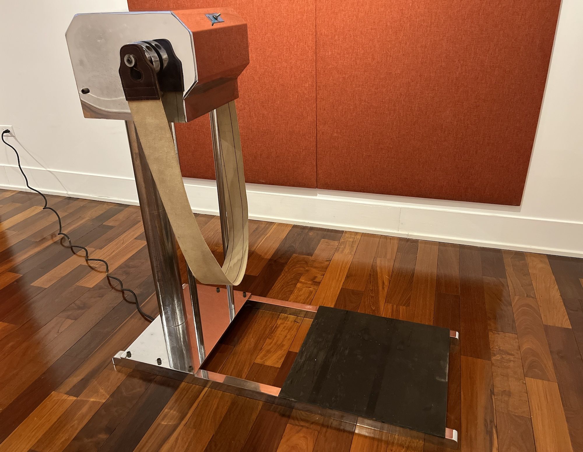 An old exercise machine on dark wood floors.
