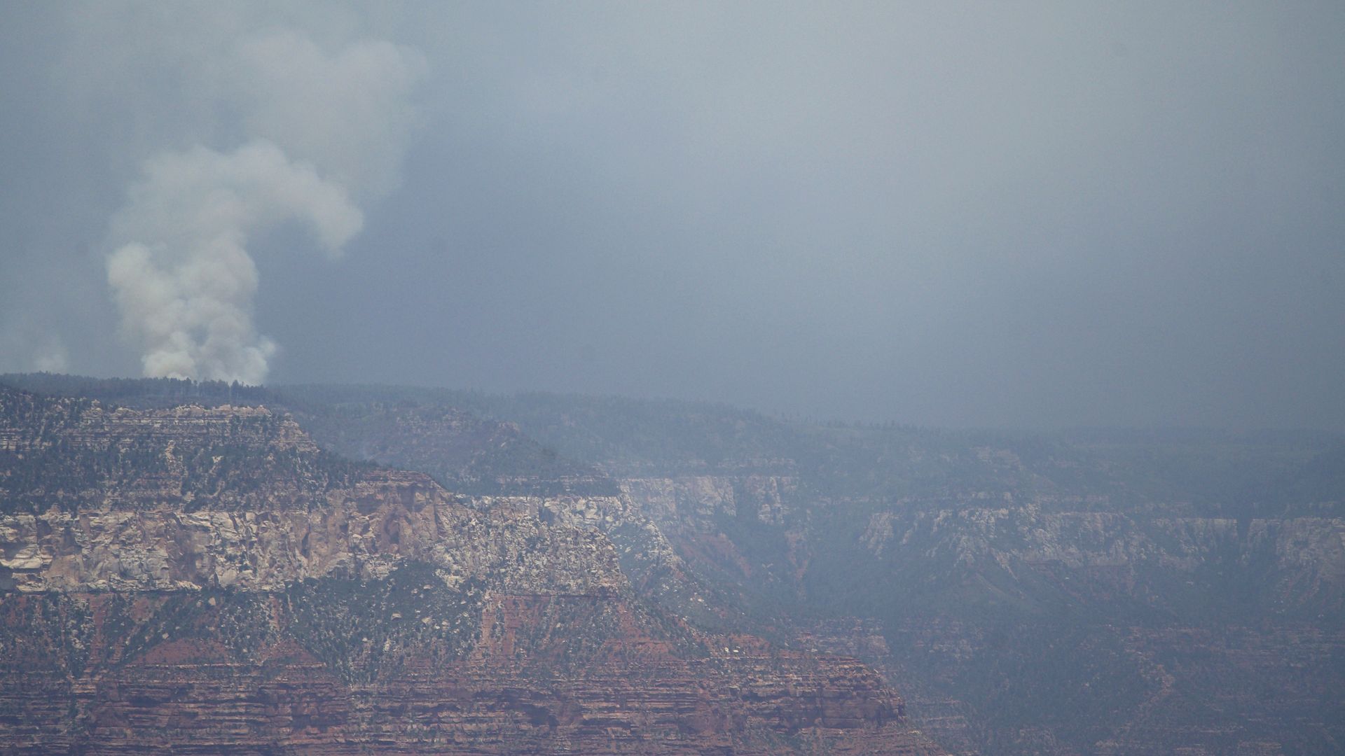 Smoke rising from a wildfire on the North Rim of the Grand Canyon and a hazy sky as seen from the South Rim.