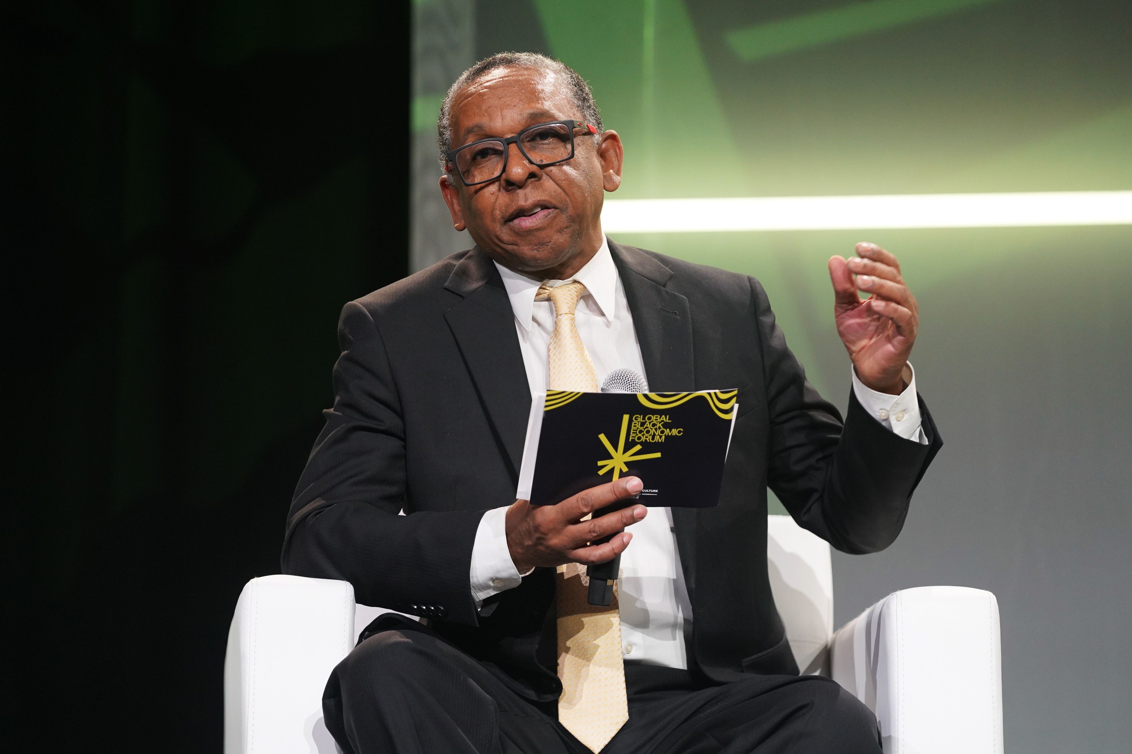 Photo shows Reynold Verret sitting on a chair on stage