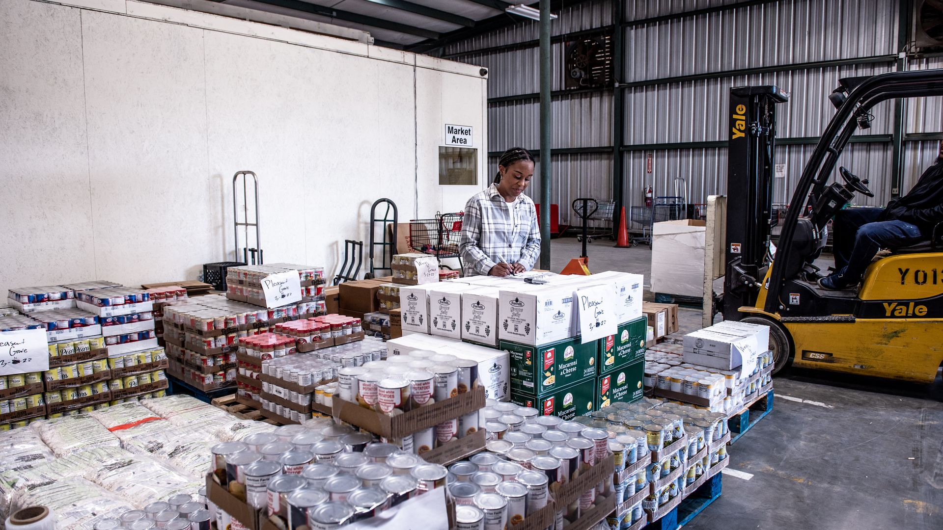 A woman signs a paper on a stack of boxes at a food bank.